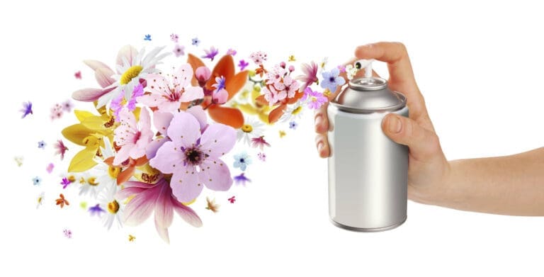 close shot of a hand with spray in hand and flowers coming out from the bottle in the gesture of odor removing with fresh air.