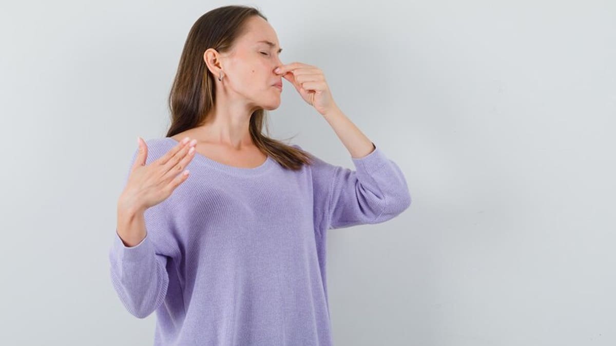 a woman pinching her nose because of smell.