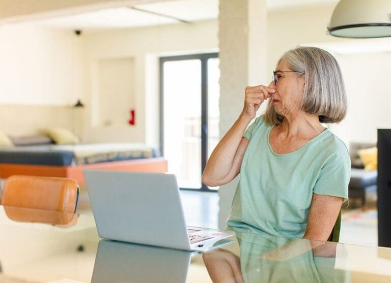 a woman pinching her nose because of smell in her house.